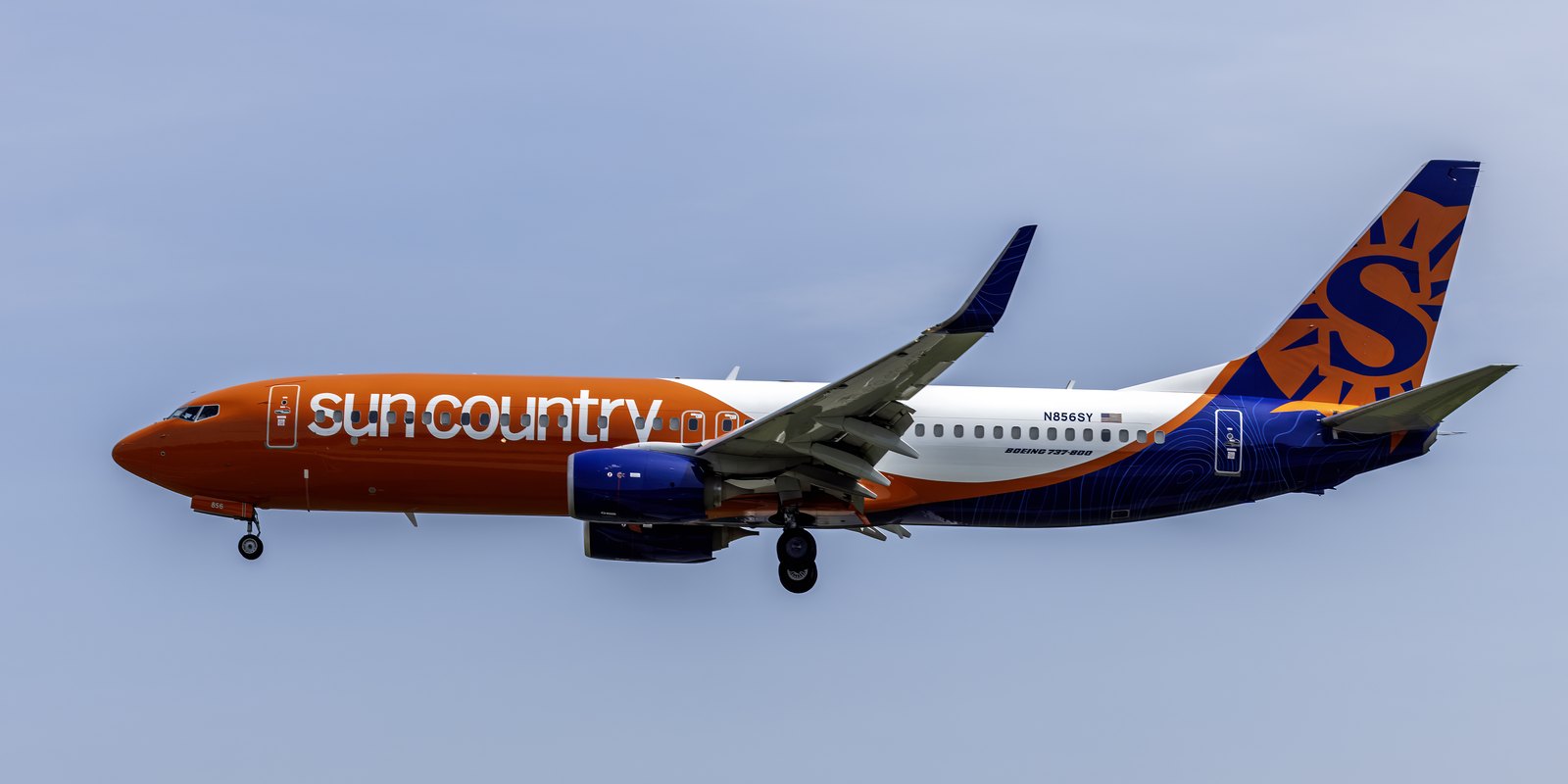 Sun Country Airlines Boeing 737-800 in flight, in orange, white and navy livery